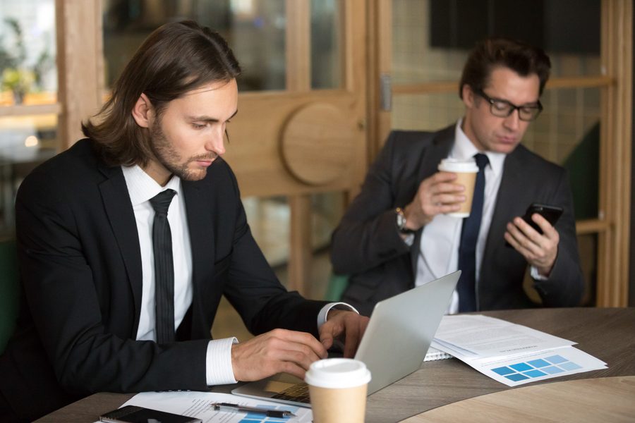 Person staring at laptop screen after job loss with bills and loan offers on table