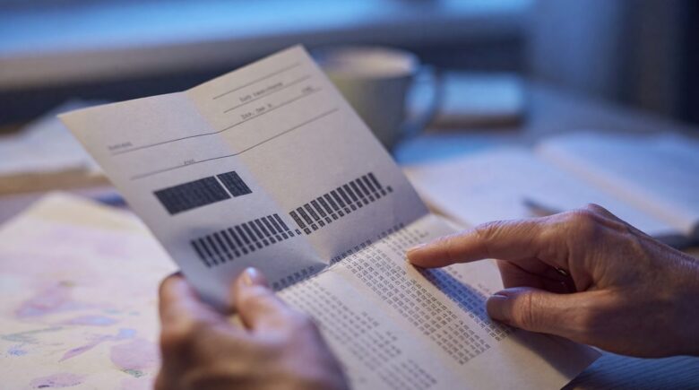 Teacher reviewing pension statement at kitchen table with financial documents