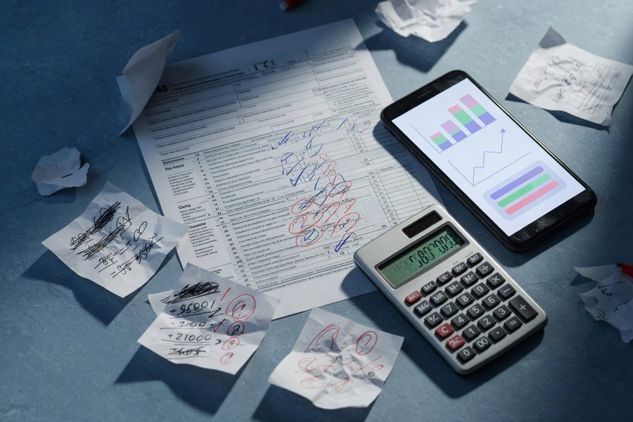A couple at a kitchen table reviewing a printed AI financial projection alongside a benefits enrollment form and a daycare contract